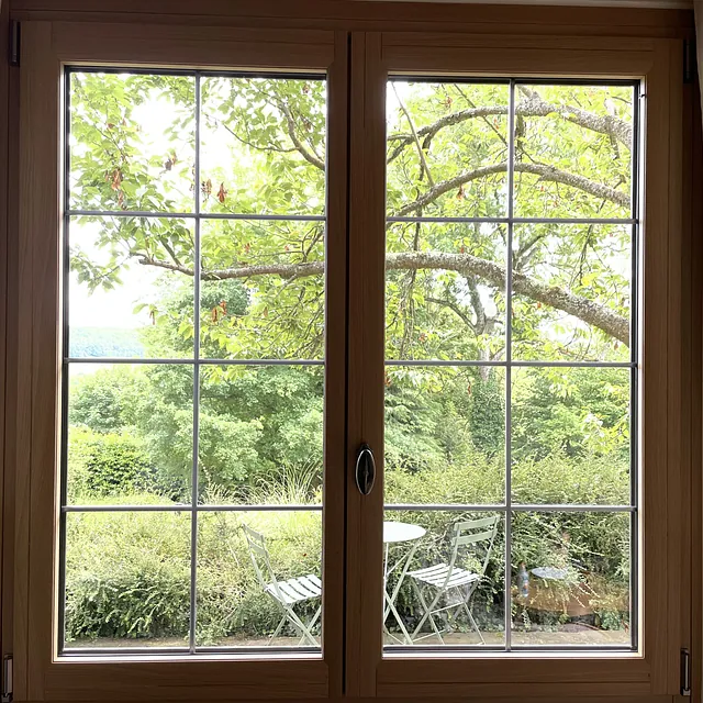 Double-fenêtre en bois clair, carreaux style géorgien, rideaux beige.